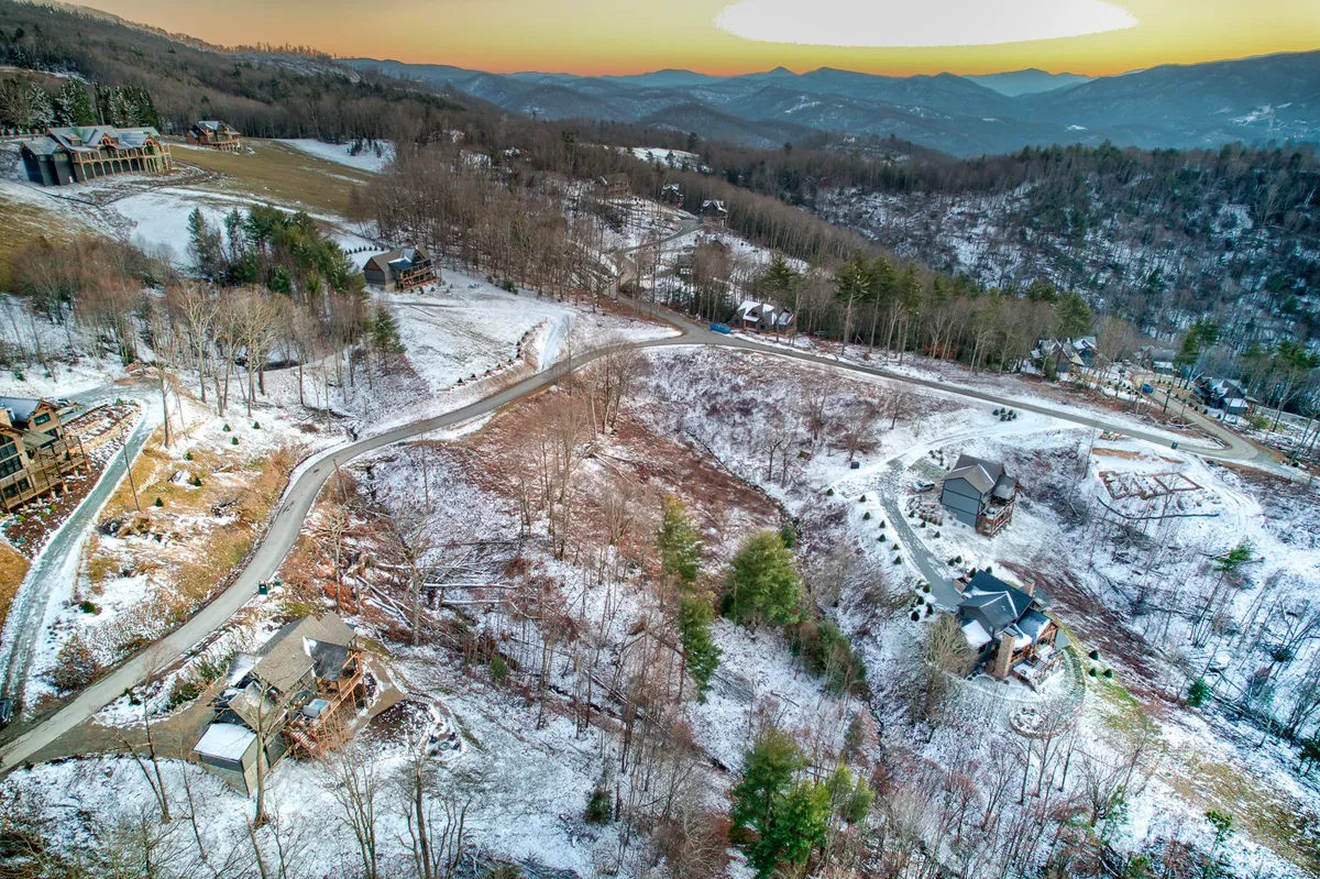 A serene, wide-angle view of the snow-covered landscape, winding road, mountain vistas, and scattered cabins. The open expanse of nature invites exploration, walking, and adventure with pets in tow.