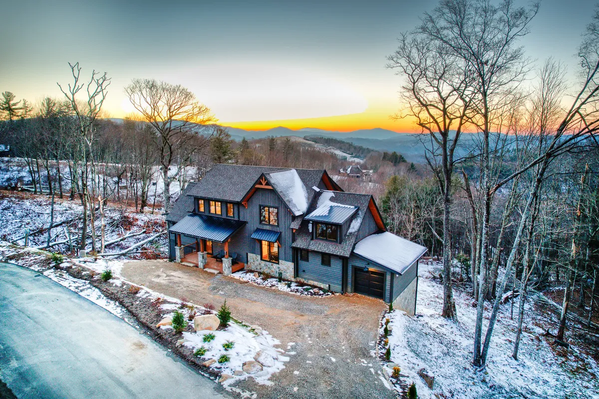 A modern house nestled in the mountains, with a sunset sky and snow-covered ground. The setting highlights opportunities for outdoor family activities and exploration.
